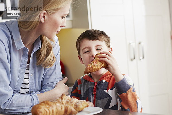 Junge beißt Croissant  Mutter schaut zu