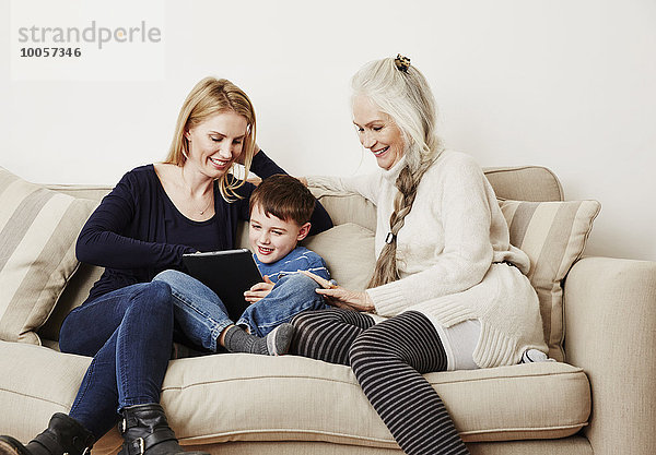 Kleiner Junge mit digitalem Tablett mit Mutter und Großmutter