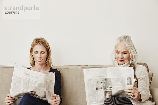 Ältere und mittlere erwachsene Frauen beim Zeitungslesen