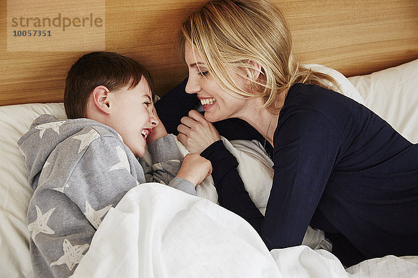Mutter und Sohn lachend im Bett