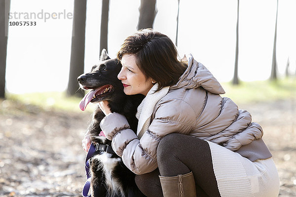 Mittlere erwachsene Frau kauernd mit ihrem Hund auf dem Feldweg