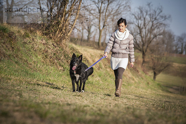 Mittlere erwachsene Frau mit ihrem Hund auf dem Feld