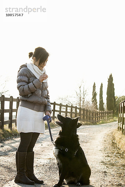 Mittlere erwachsene Frau Gehorsam Ausbildung ihres Hundes auf dem Landweg