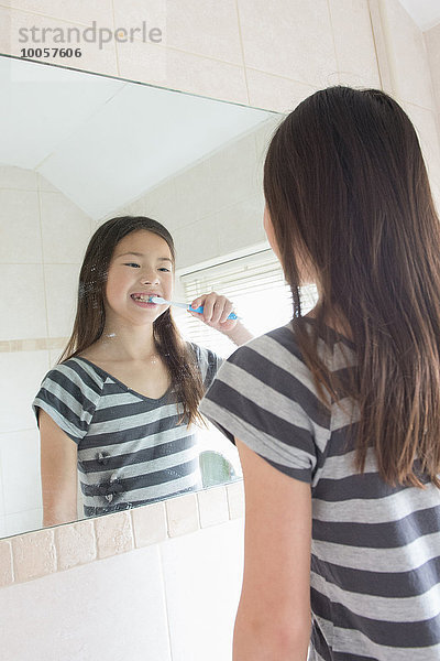 Mädchen beim Zähneputzen im Badezimmerspiegel