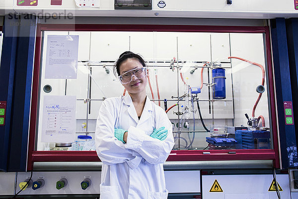 Porträt einer jungen Wissenschaftlerin vor dem Abzug im Labor