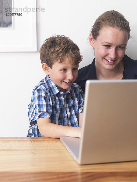 Junge Frau und Sohn benutzen gemeinsam den Laptop zu Hause.