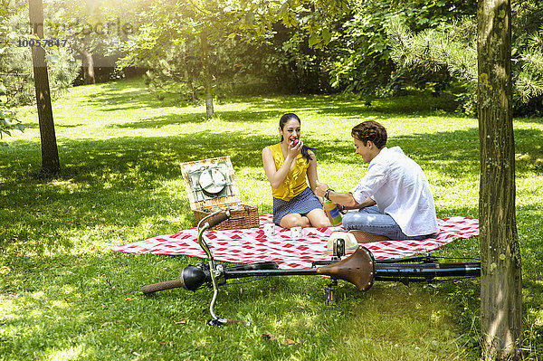 Junges Paar sitzend beim Picknick auf der Decke