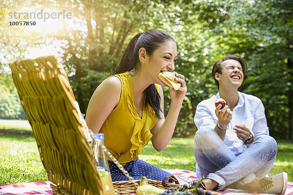 Junges Paar sitzend beim Picknick lachend