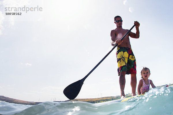 Ebenerdige Ansicht des jungen Mannes und der Kleinkind-Tochter Standup Paddleboarding