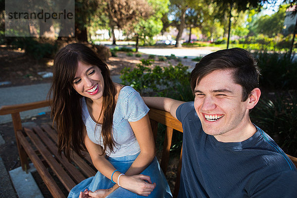 Junges Paar lacht auf Parkbank