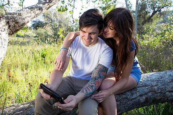 Junges Paar beim Durchstöbern des digitalen Tabletts im Park