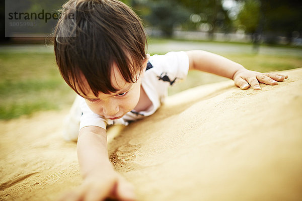 Nahaufnahme eines Jungen beim Klettern auf einen Sandfelsen