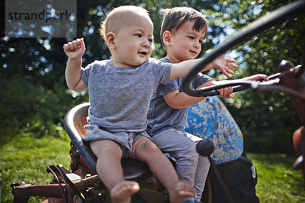Junge und Junge spielen auf dem alten Traktor
