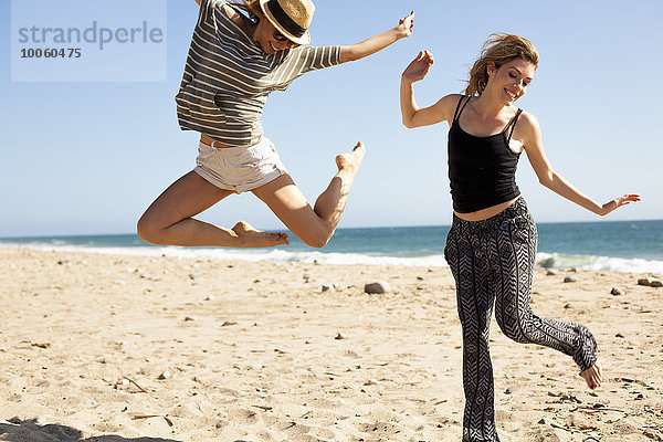 Freundinnen springen in der Luft am Strand  Malibu  Kalifornien  USA