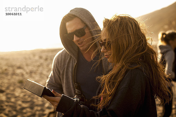 Paar mit digitalem Tablett am Strand