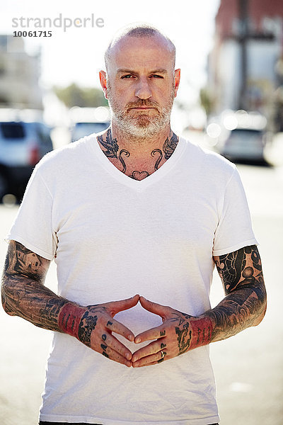 Reifer Mann mit Tattoos an Armen und Hals