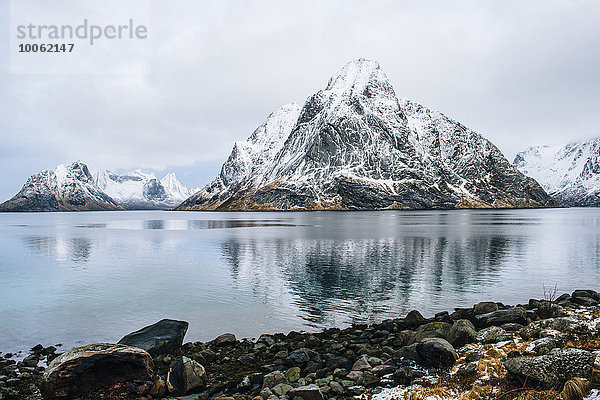 Blick auf schneebedeckte Berge und Felsenküste  Reine  Lofoten  Norwegen