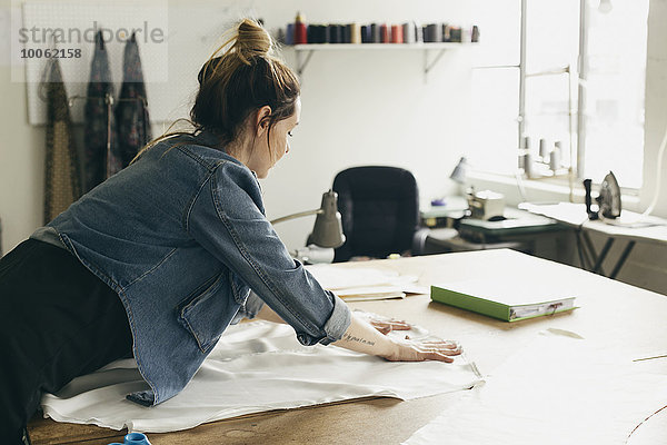 Junge Näherin beim Auslegen von Schnittmusterteilen im Modestudio