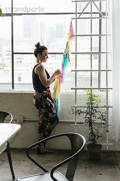 Junge Designerin  die im Designstudio eine mehrfarbige Fahne herstellt