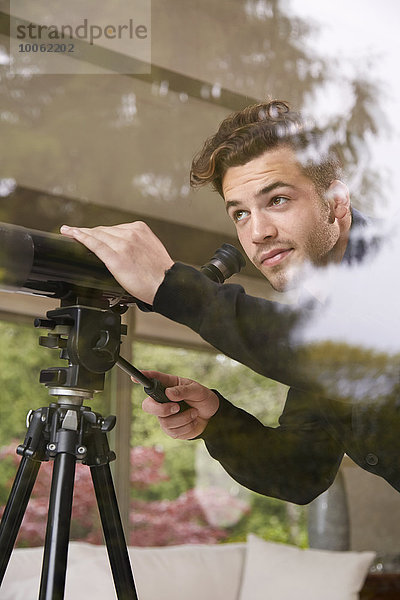 Porträt eines Mannes mit Teleskop aus dem Fenster schauend
