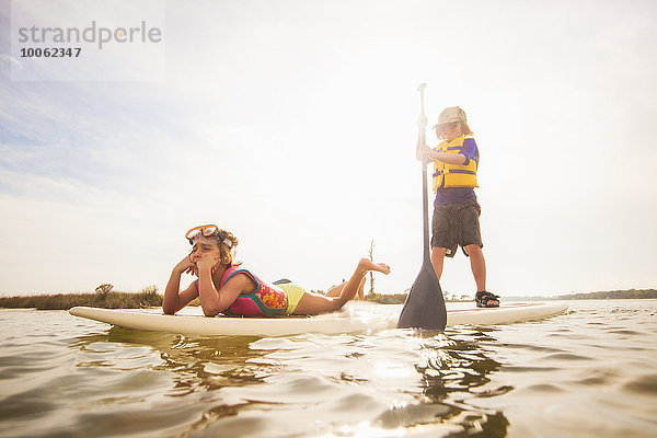 Boy standup paddleboarding mit Schwester im Sound  Fort Walton  Florida  USA