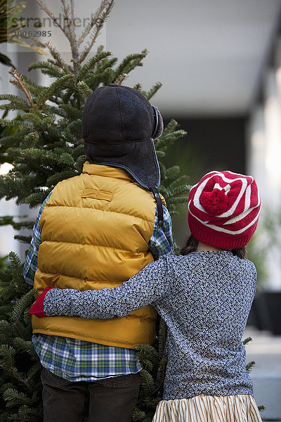 Mädchen und Junge mit Weihnachtsbaum