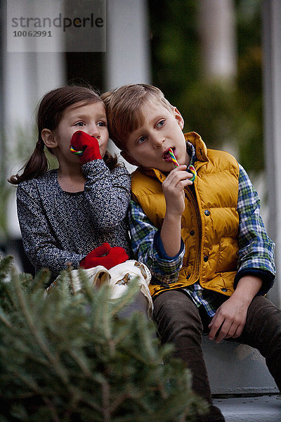 Porträt eines Jungen und Mädchens beim Essen von festlichen Zuckerstangen