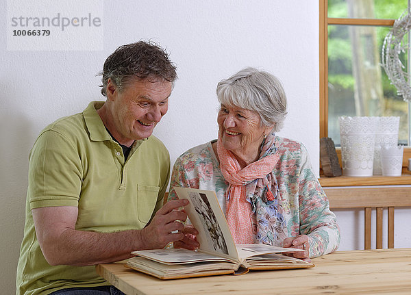 Erwachsener Sohn und ältere Mutter schauen ein Fotoalbum an  Bayern  Deutschland  Europa