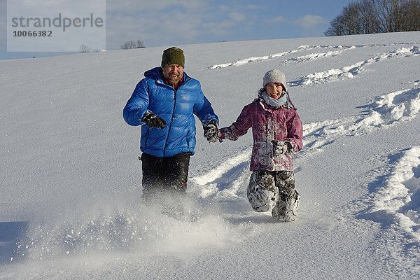 Vater und Tochter laufen im tiefen Schnee  Bad Heilbrunn  Oberbayern  Bayern  Deutschland  Europa