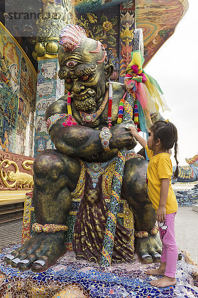 Mädchen reibt Geldschein an einer Yaksa Statue  Yak  Elefanten-Tempel Thep Wittayakhom Vihara  Wittayakom  Wat Baan Rai  Korat  Nakhon Ratchasima Provinz  Isaan  Isan  Thailand  Asien