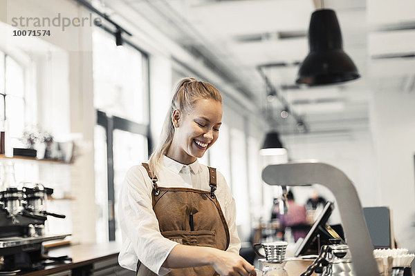 Fröhliche weibliche Barista bei der Kaffeezubereitung im Cafe