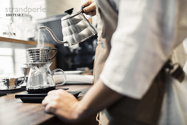 Seitenansicht Mittelteil des Barista mit kochendem Wasser im Kaffeefilter