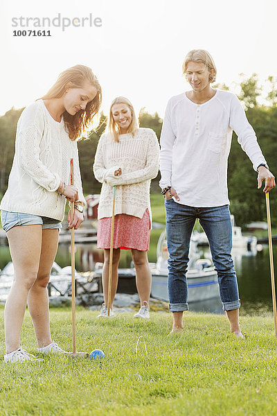 Freunde spielen Krocket auf dem Feld gegen den klaren Himmel.