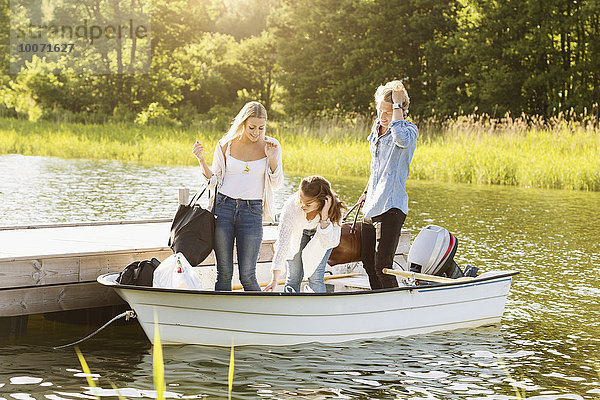 Glückliche Freunde mit Gepäck genießen im Boot auf dem See