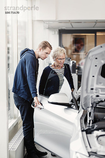 Mutter und Sohn schauen sich das Auto im Autohaus an