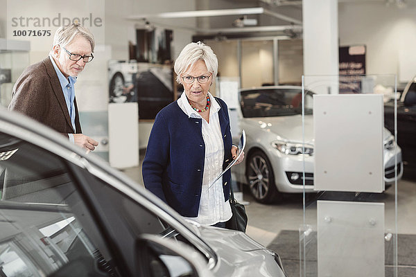 Seniorenpaar beim Betrachten des Autos im Ausstellungsraum