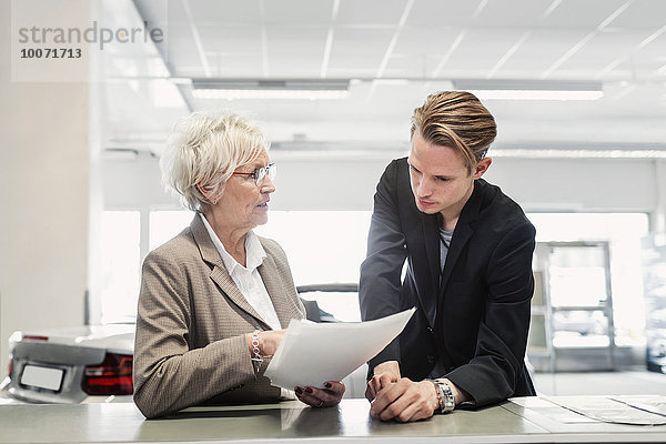 Zwei Vertriebskollegen besprechen Dokumente im Autohaus