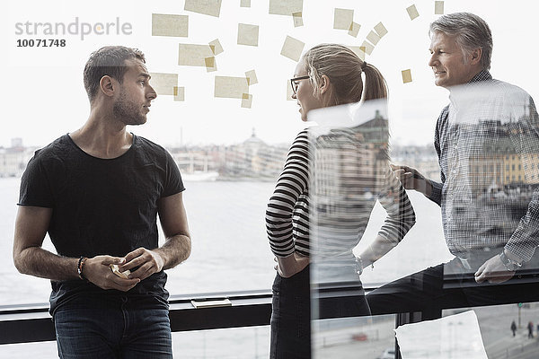 Geschäftskollegen diskutieren am Glasfenster im Büro