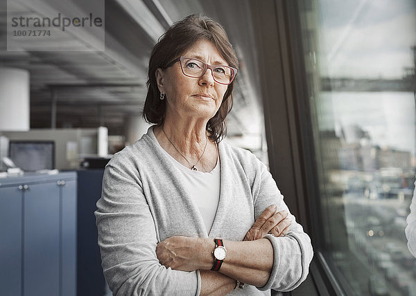 Porträt einer selbstbewussten Senior-Geschäftsfrau  die im Büro am Fenster steht.
