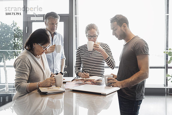 Geschäftsleute  die beim Kaffeetrinken an der Theke im Bürocafé arbeiten