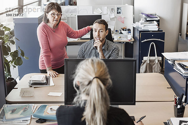 Geschäftsleute diskutieren am Schreibtisch im Büro