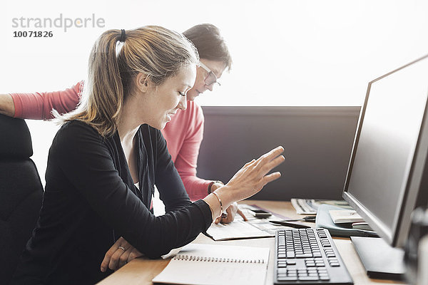 Geschäftsfrauen diskutieren am Computertisch im Büro