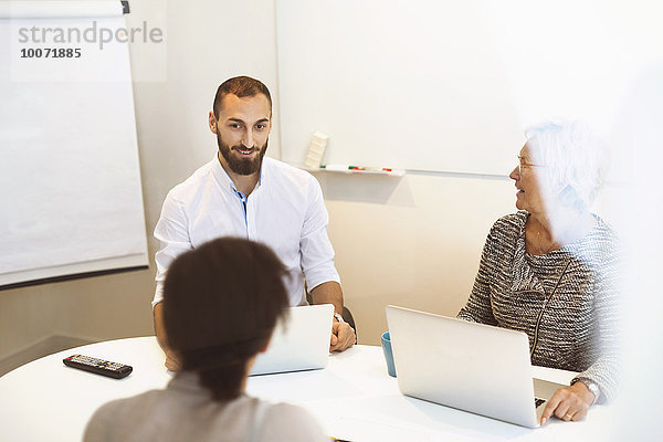 Geschäftsleute mit Laptops am Konferenztisch im Büro