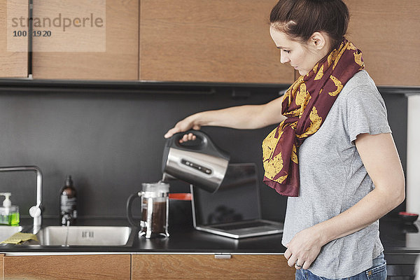Seitenansicht der Frau bei der Kaffeezubereitung in der Küche