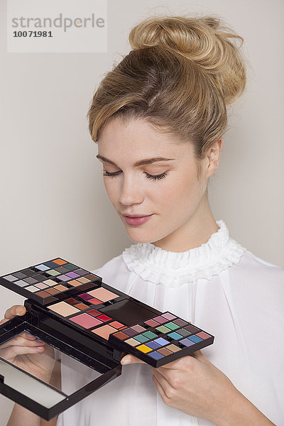 Schöne Frau mit Blick auf Lidschatten-Palette