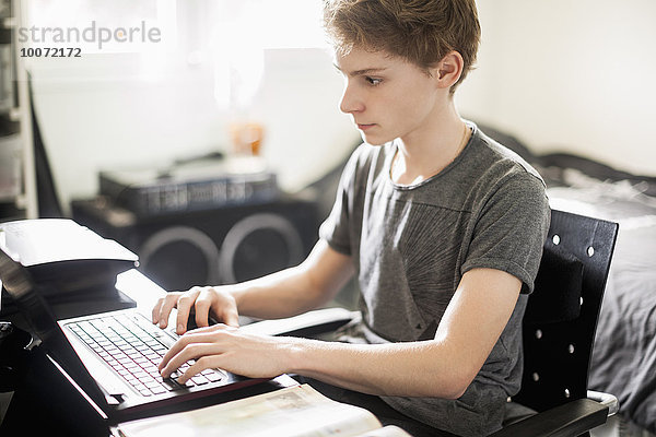 Teenager Jungen schreiben auf dem Laptop