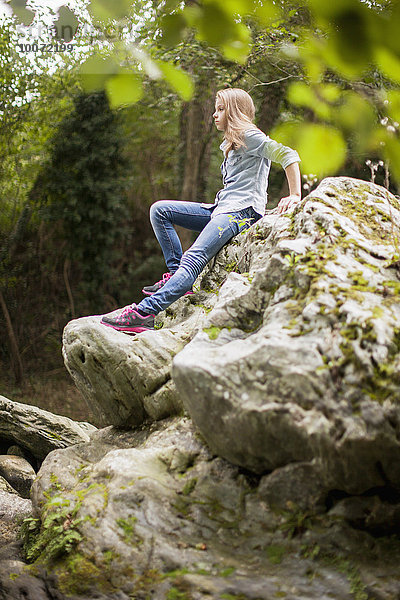 Mädchen sitzt auf einem Felsen in einem Park