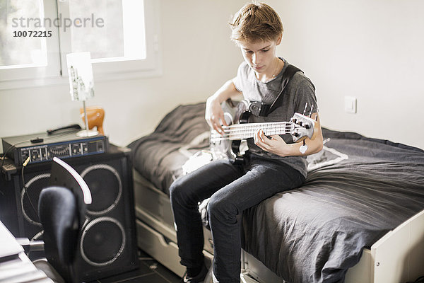 Teenager-Junge spielt Gitarre im Bett
