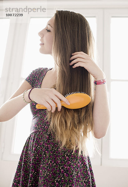 Teenagermädchen bekommt Haarpflege mit Bürste