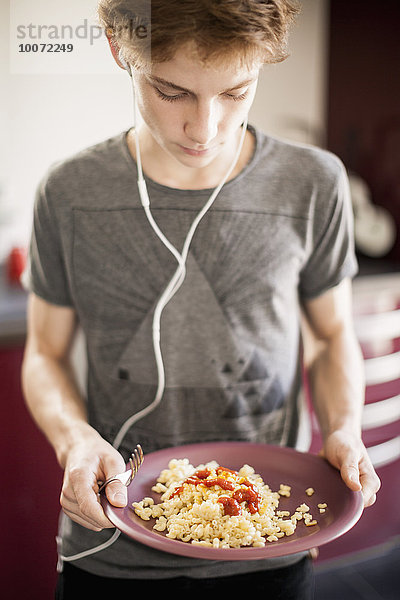 Teenager Junge hört Musik mit Frühstück